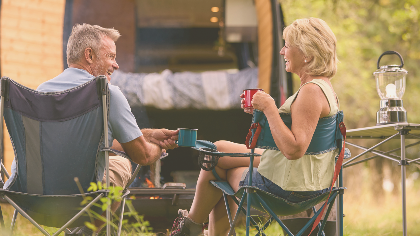 Rear view of a senior couple camping in the countryside with their RV, enjoying a casual outdoor RV adventure.